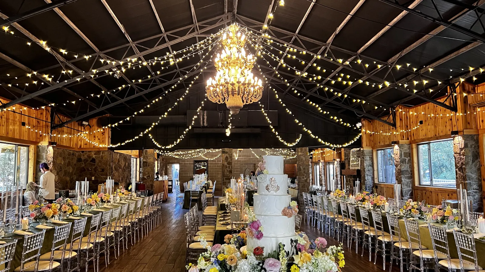 Wedding reception hall with a chandelier and string lights, set for an evening event